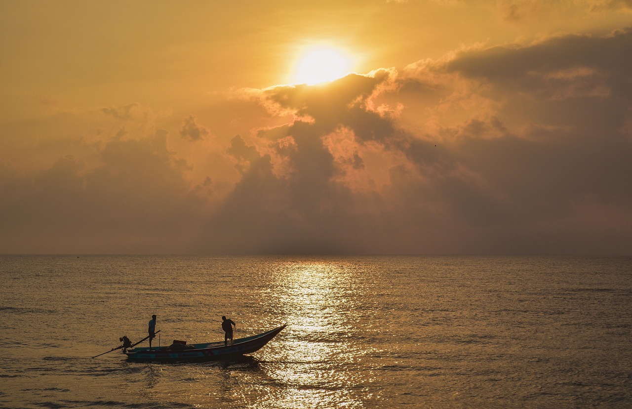 A fishing boat silhouetted against a golden sunrise over the sea off Pondicherry.